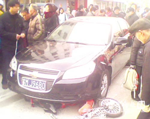 肇事“雪佛兰”将电动车压在身下。 汤央 王国柱 摄