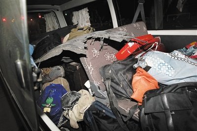 一辆停放在滨保高速入口的面包车上装满了遇难者的遗物，包括书包、电脑包以及爆裂的轮胎残骸。吴江摄